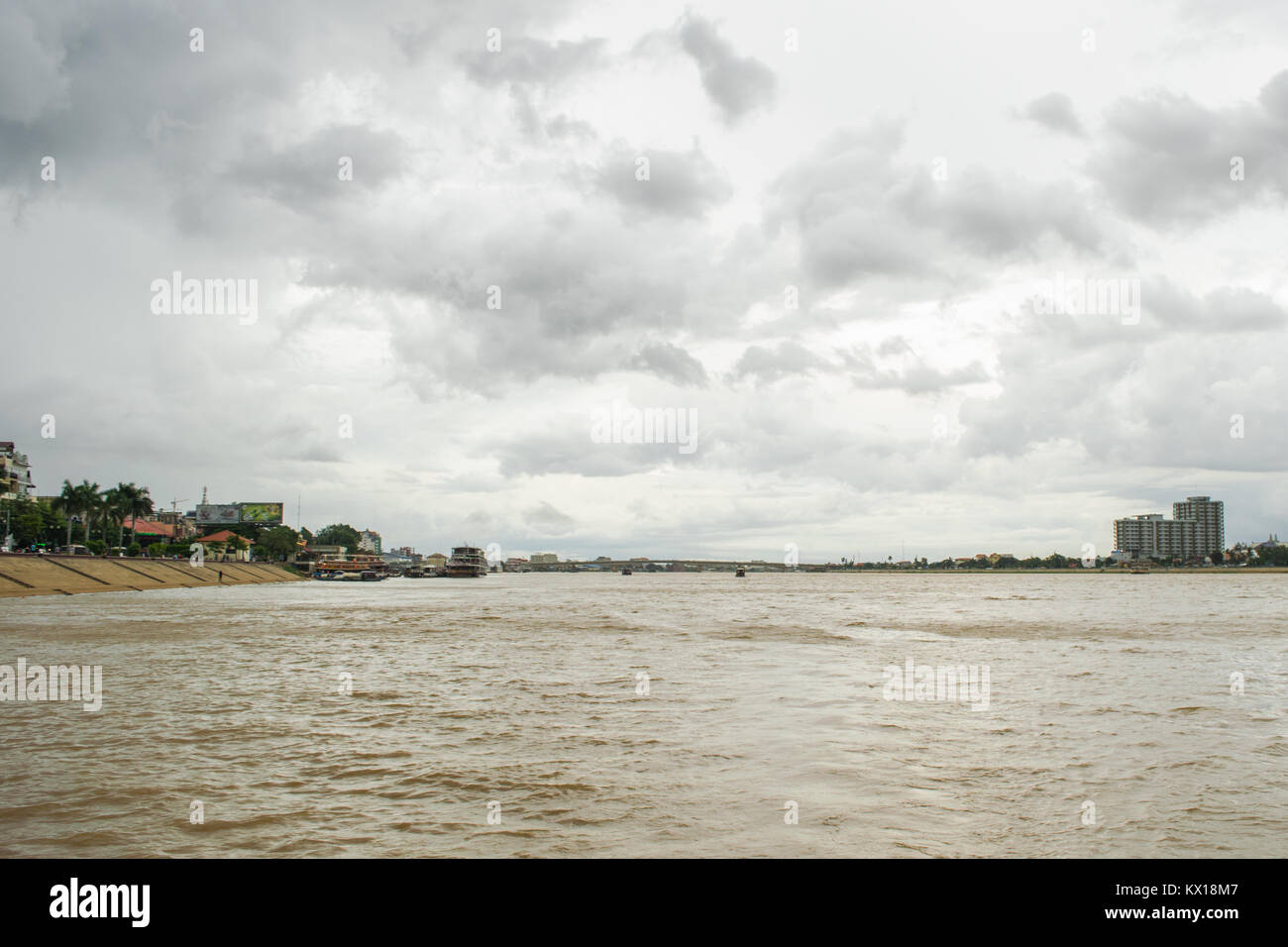 Über den Tonle Sap Fluss mit dem Boot in Phnom Penh, Kambodscha, mit bewölkt regen Himmel während der Monsunzeit, Japan Kambodscha Friendship Bridge in der Entfernung Stockfoto
