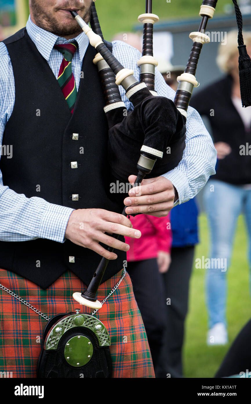 Ein Schottischer Mann mit Kilt bekleidet, den Dudelsack zu spielen auf einem Festival. Stockfoto