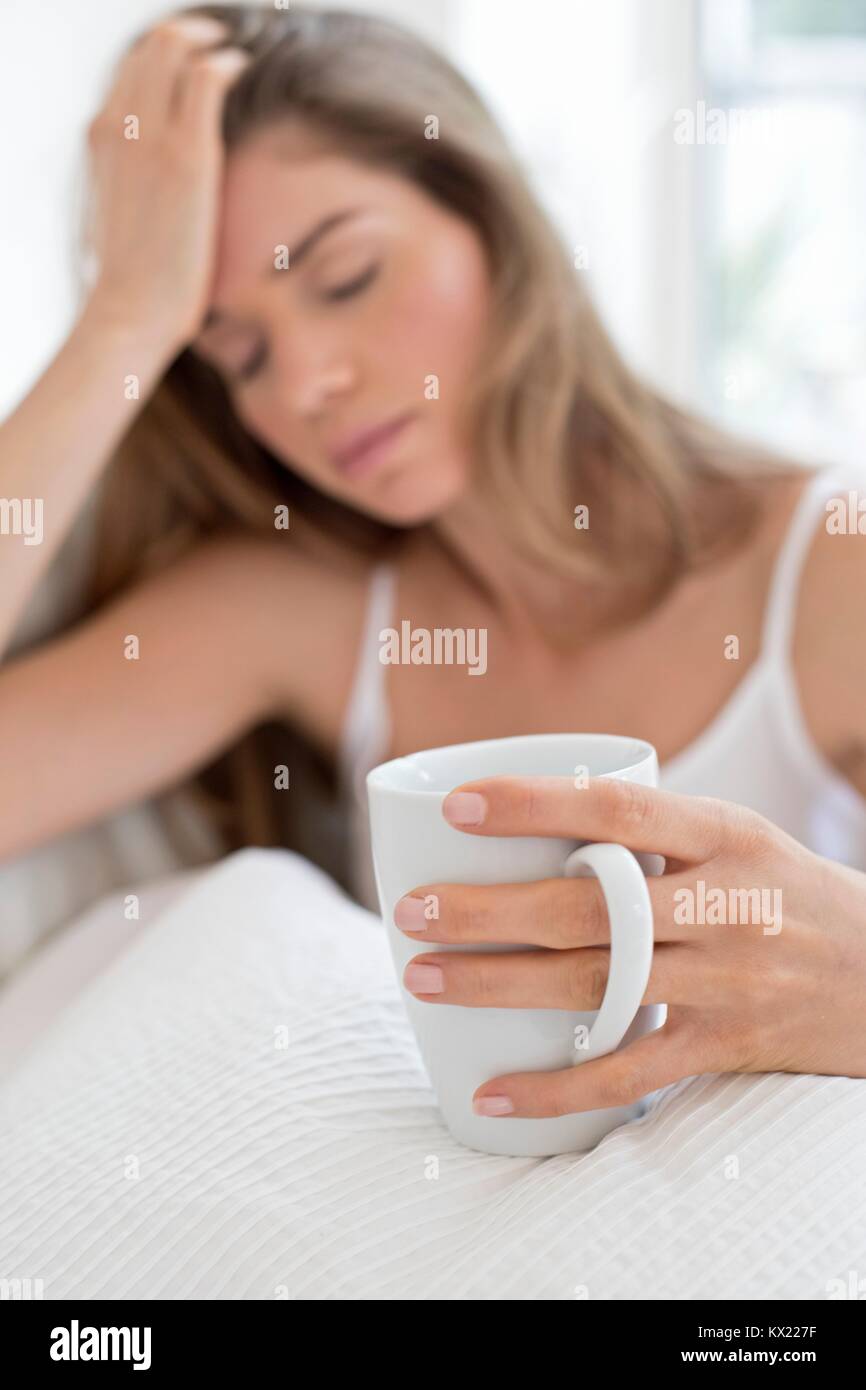 MODEL RELEASED. Junge Frau im Bett mit Kaffee. Stockfoto
