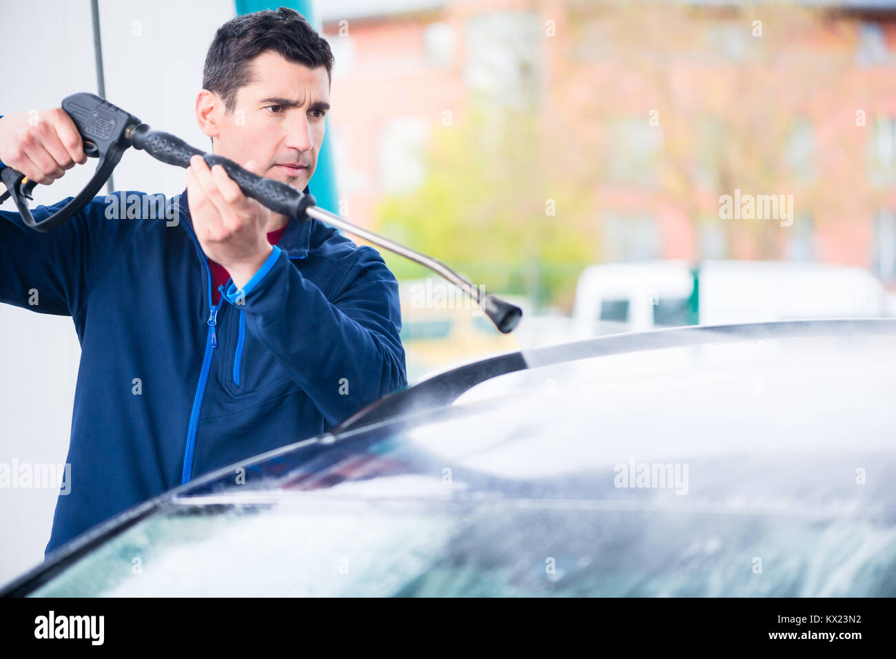 Engagierte Mitarbeiter waschen Auto mit Hochdruckschlauch Stockfoto