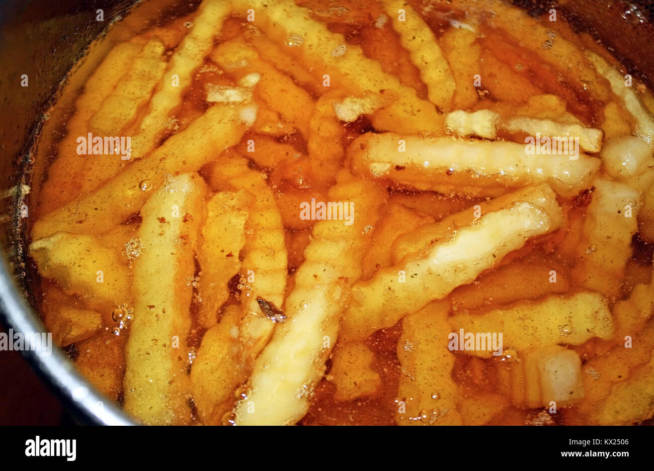Crinkle Cut Pommes frites sitzt in einem Topf mit Öl in der Friteuse Stockfoto