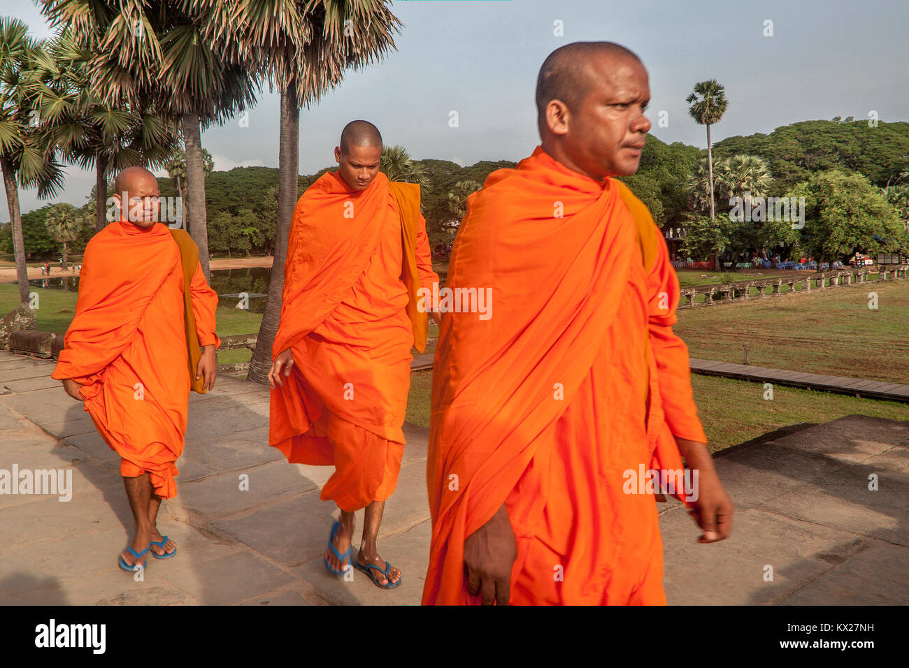 Drei buddhistischen Mönchen in den traditionellen Safran Seide Gewänder gekleidet zu Fuß den Sandstein Straße in die Tempel Angkor Wat, Siem Reap, Kambodscha. Stockfoto
