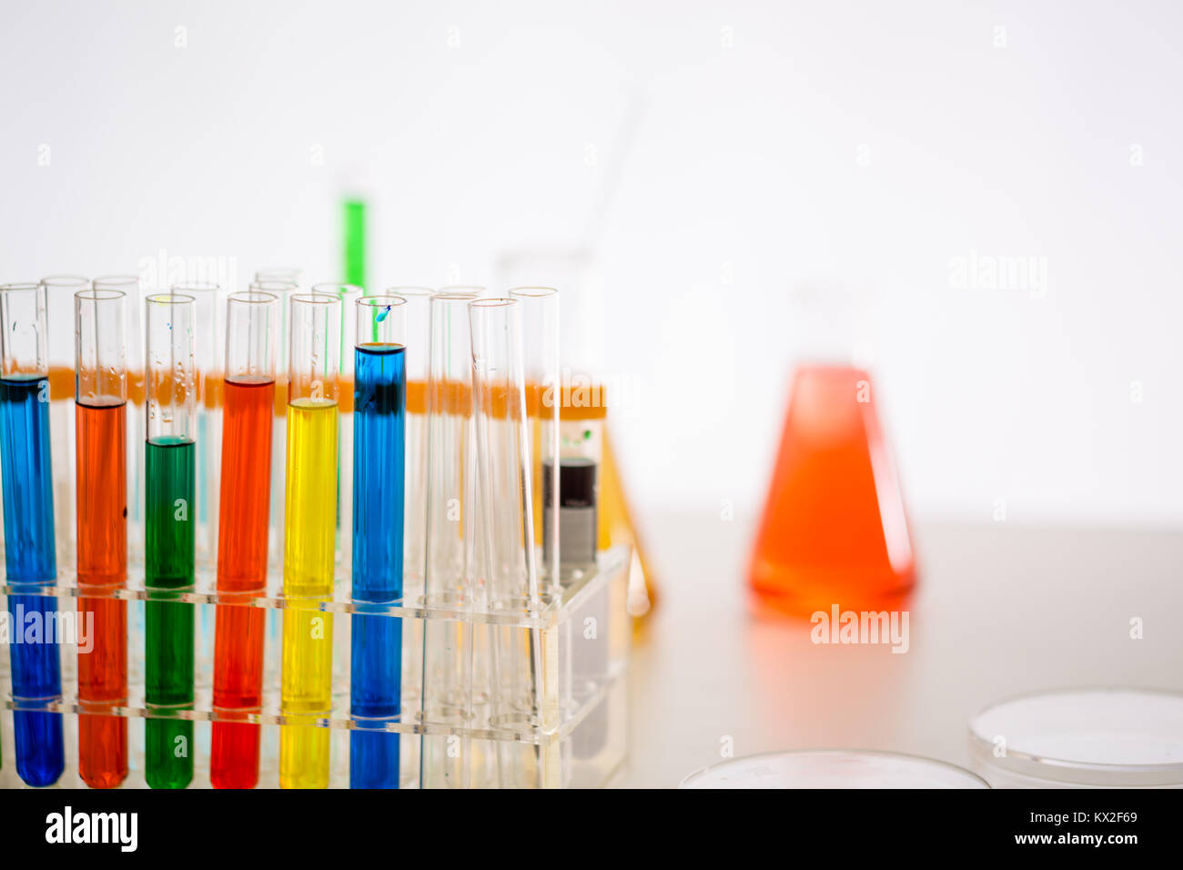 Reihen von bunten Röhrchen auf Lab Tabelle mit Erlenmeyerkolben im Hintergrund Stockfoto