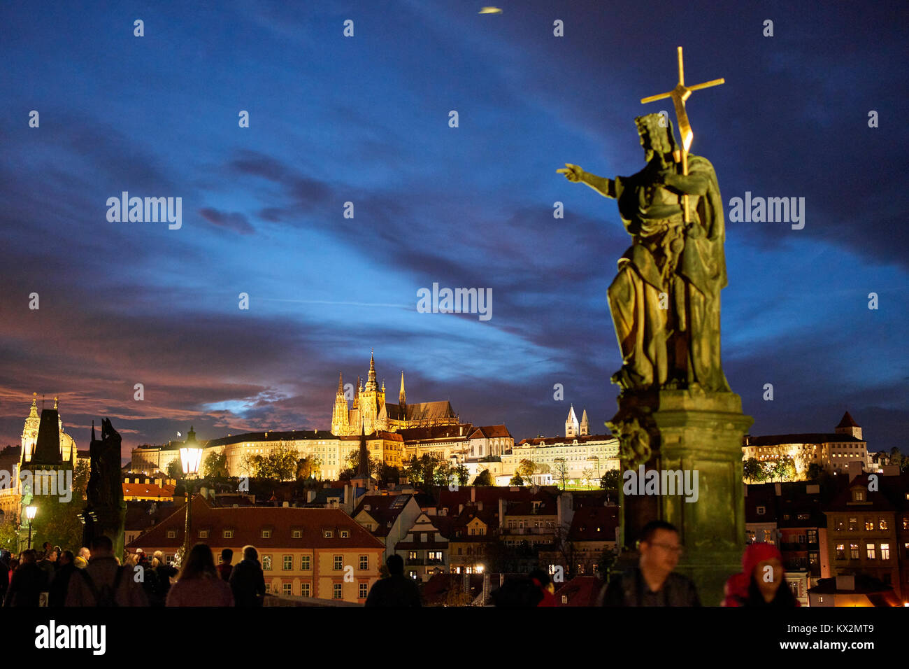 Die Prager Burg im Abendlicht von der Charles Brücke gesehen mit Statue von Johannes dem Täufer von Josef Max Holding ein Kreuz auf der Burg zeigen Stockfoto