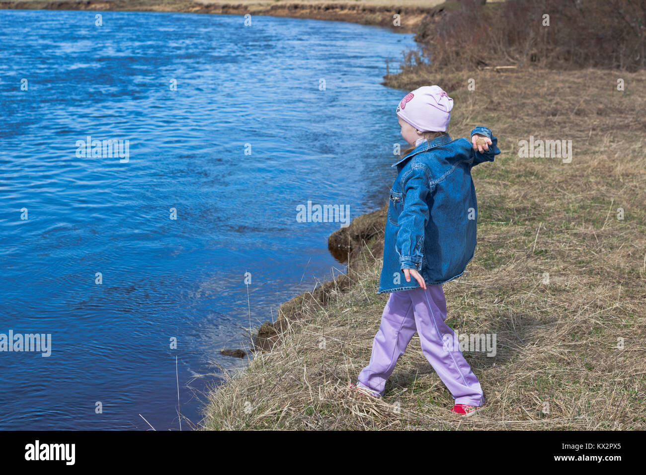 Mädchen spielen am Ufer des Flusses und wirft Steine ins Wasser Stockfoto