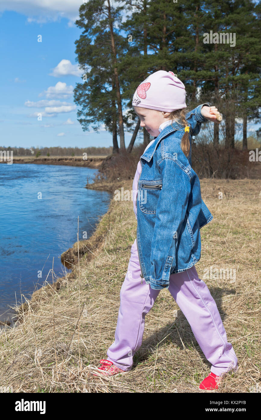 Kleine Mädchen spielen am Ufer des Flusses und wirft Steine ins Wasser Stockfoto