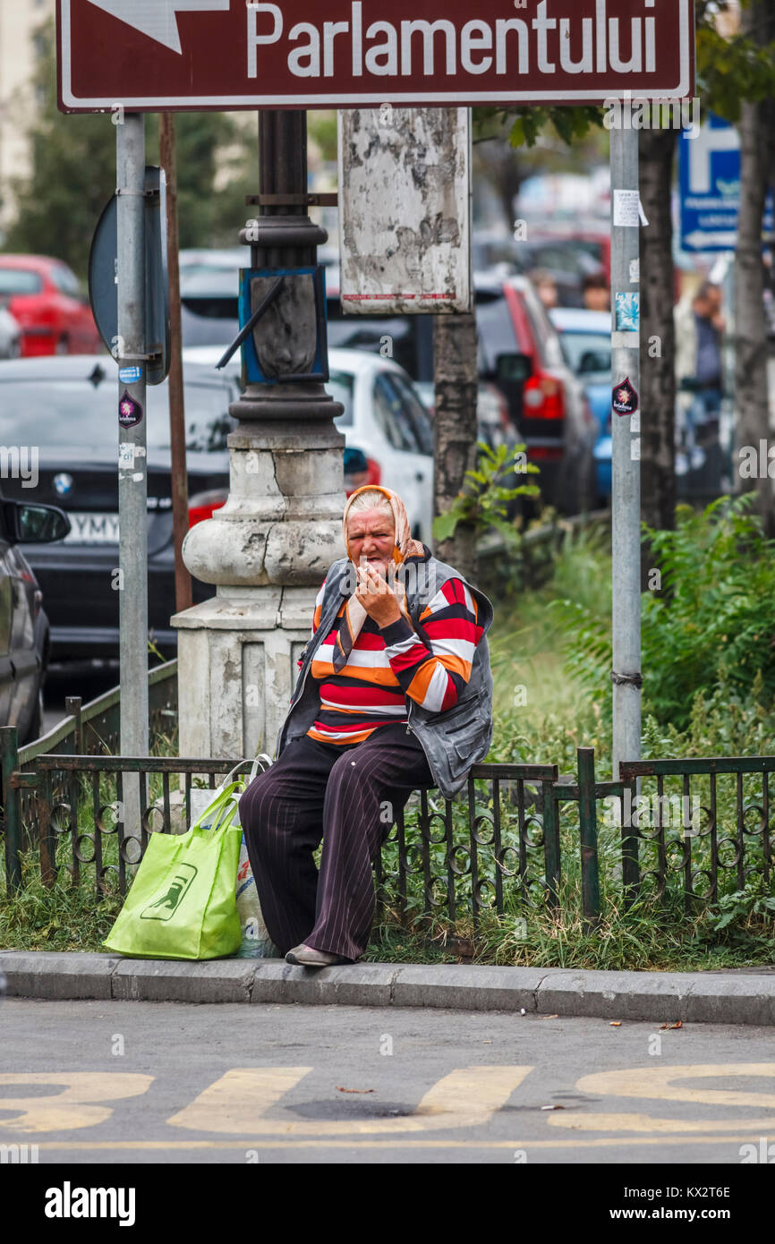 Die alte Frau am Straßenrand auf Geländer rauchen in der Innenstadt von Bukarest, der Hauptstadt Rumäniens, Mitteleuropa Stockfoto