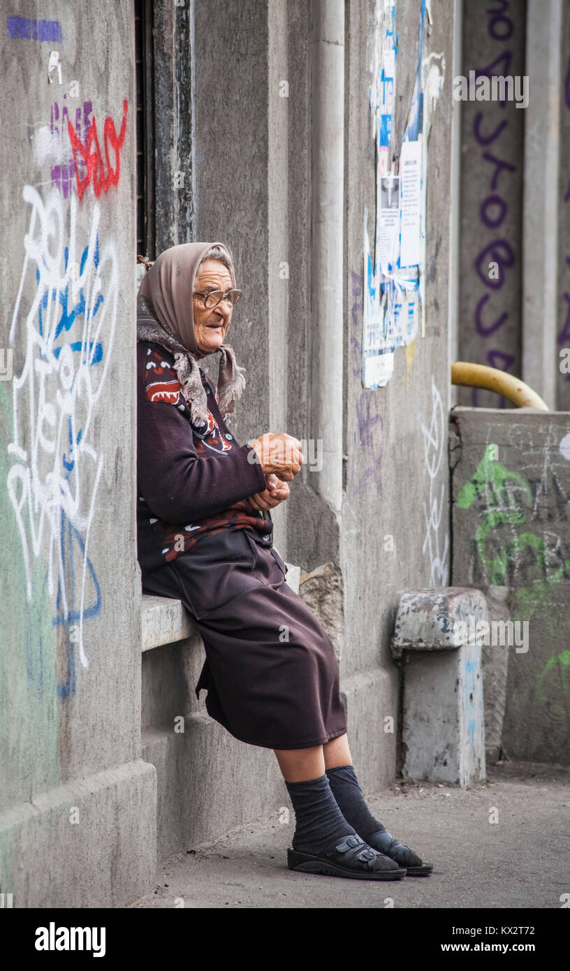 Lokale Lebensstil: armen alten Frau sitzt auf einem Fenstersims mit Graffiti betteln von Passanten in Bukarest, der Hauptstadt Rumäniens, Mitteleuropa Stockfoto