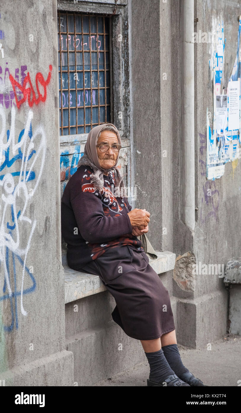 Lokale Lebensstil: armen alten Frau sitzt auf einem Fenstersims mit Graffiti betteln von Passanten in Bukarest, der Hauptstadt Rumäniens, Mitteleuropa Stockfoto