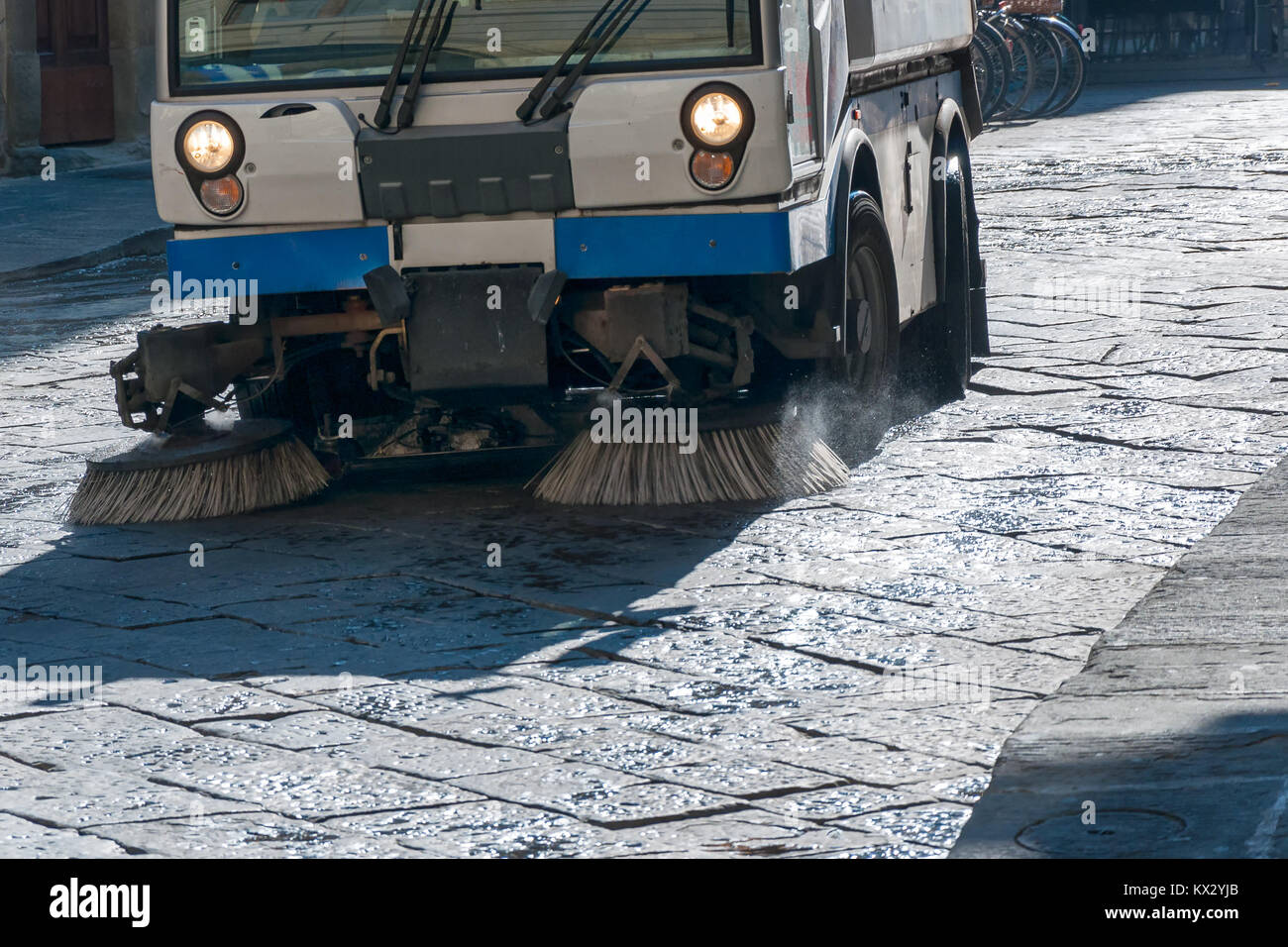 Eine Straßenkehrmaschine Fahrzeug bei der Arbeit Reinigung gepflasterten Straße Stockfoto