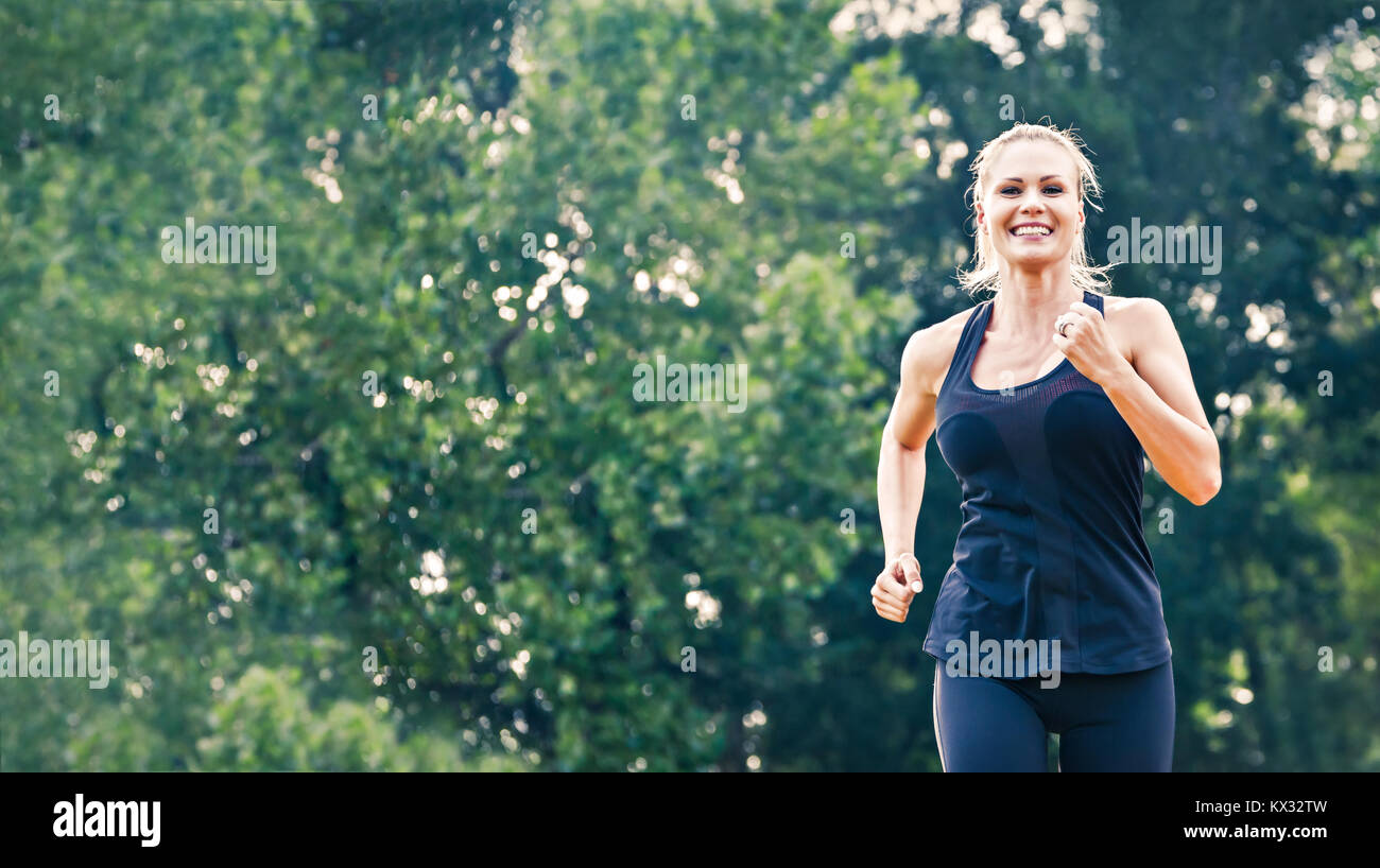 Blonde junge Frau im Park läuft Stockfoto