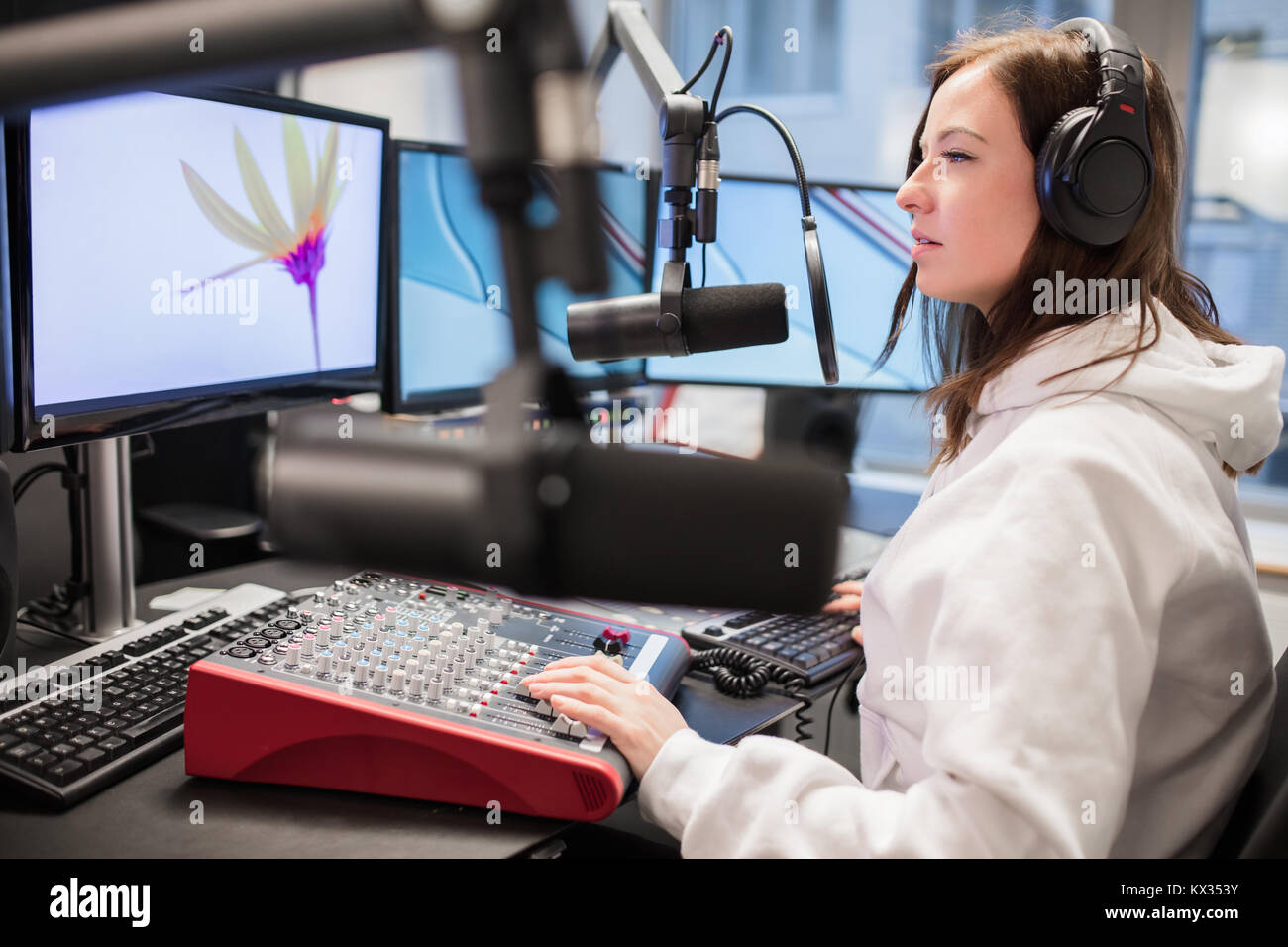 Host über Kopfhörer und Mikrofon während bei Monitor suchen Stockfoto