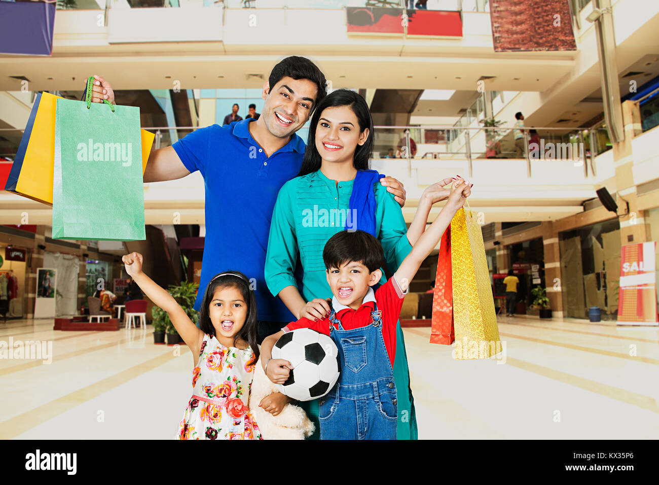 Glückliche Familie mit Kindern Durchführung Einkaufstüten kaufen In Mall Stockfoto