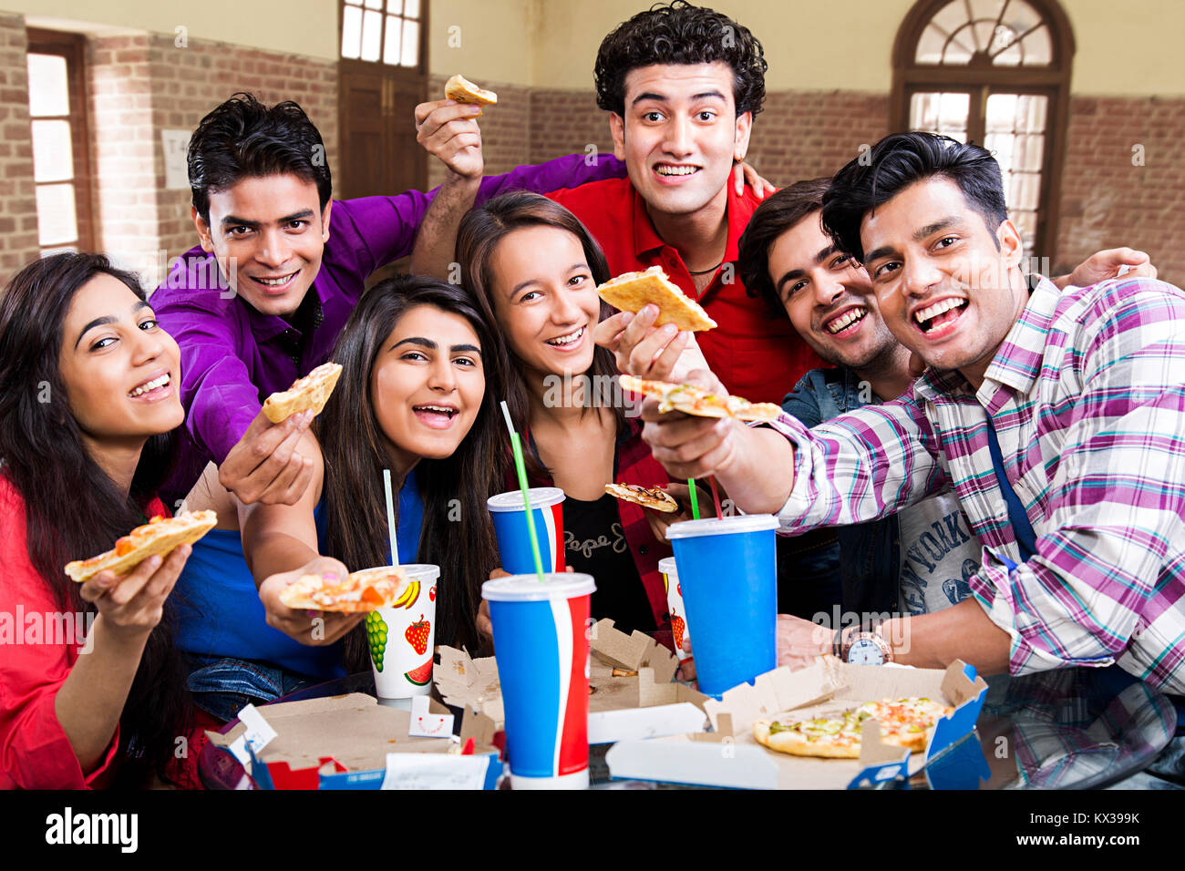 Indische Gruppe Freunde, die Pizza Essen Cafeteria glücklich Genießen Stockfoto