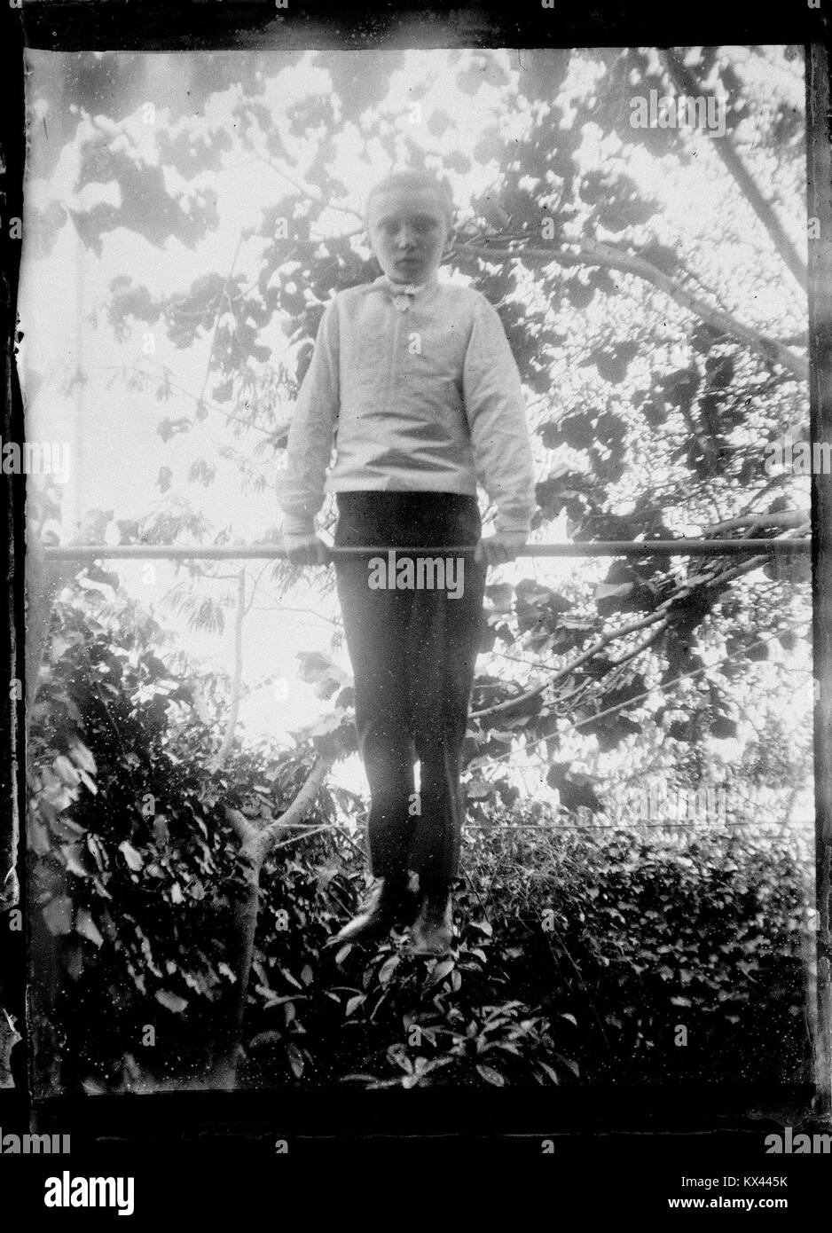 Eine Fotografie aus der Sammlung des Fonds Berthelé, die Raoul Berthelé als Kind zeigt, das auf einer horizontalen Bar auftritt und die Kindheit und körperliche Bewegung des frühen 20. Jahrhunderts reflektiert. Stockfoto