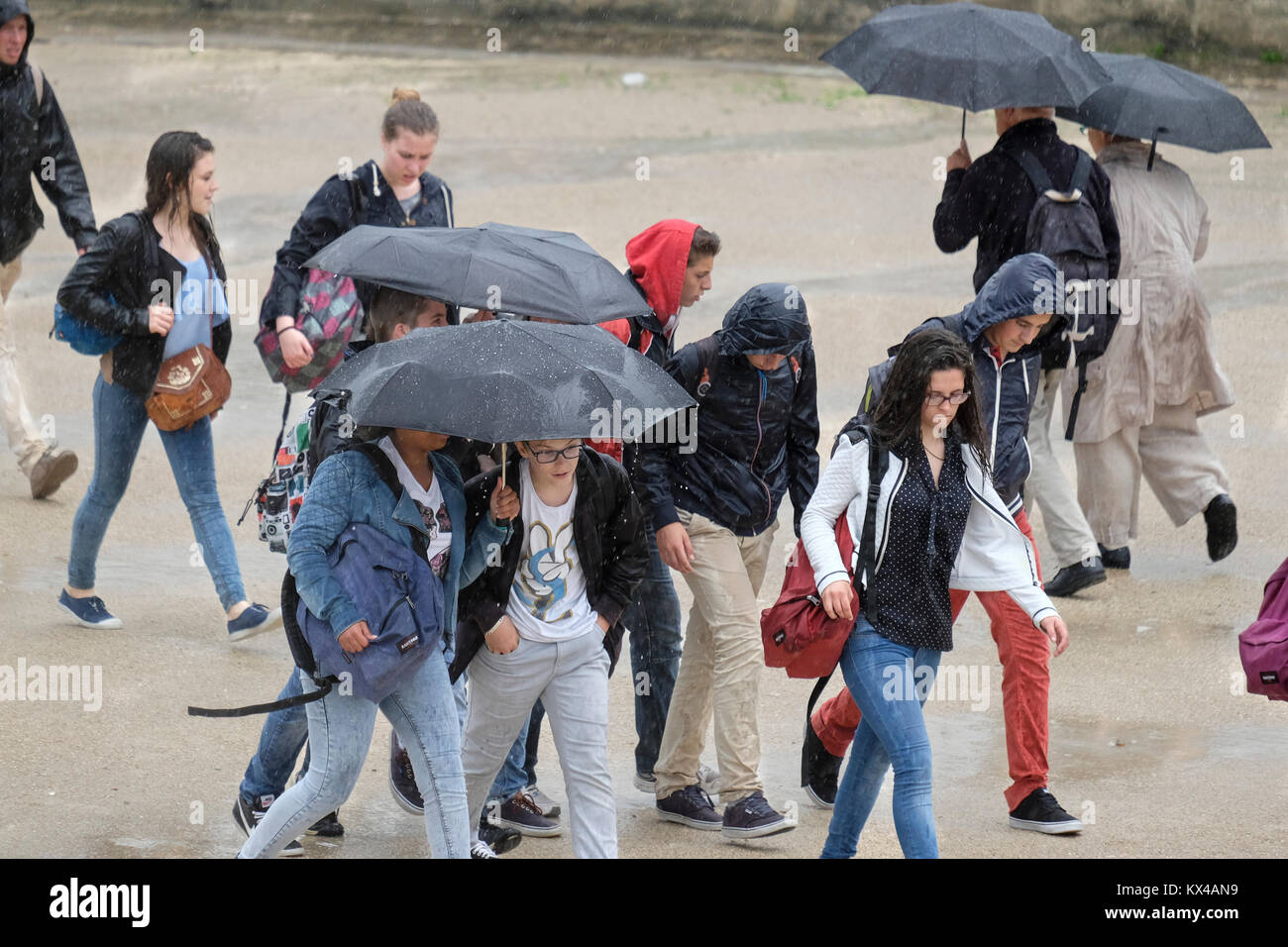 Eine Gruppe von Jugendlichen in einem Regenguß, Paris, Frankreich gefangen Stockfoto