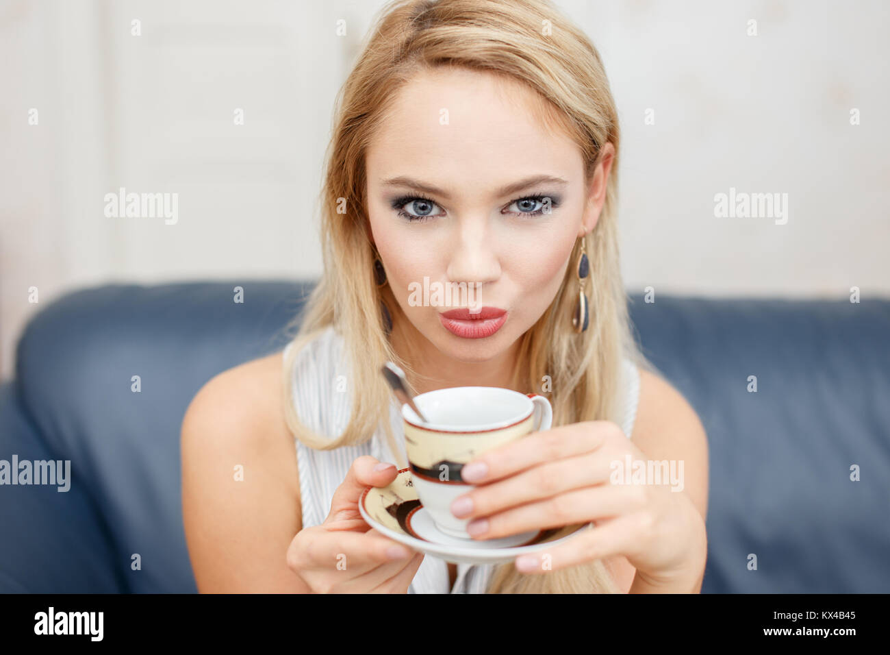 Junge kaukasier blonde Frau trinkt Kaffee in Innenräumen Stockfoto