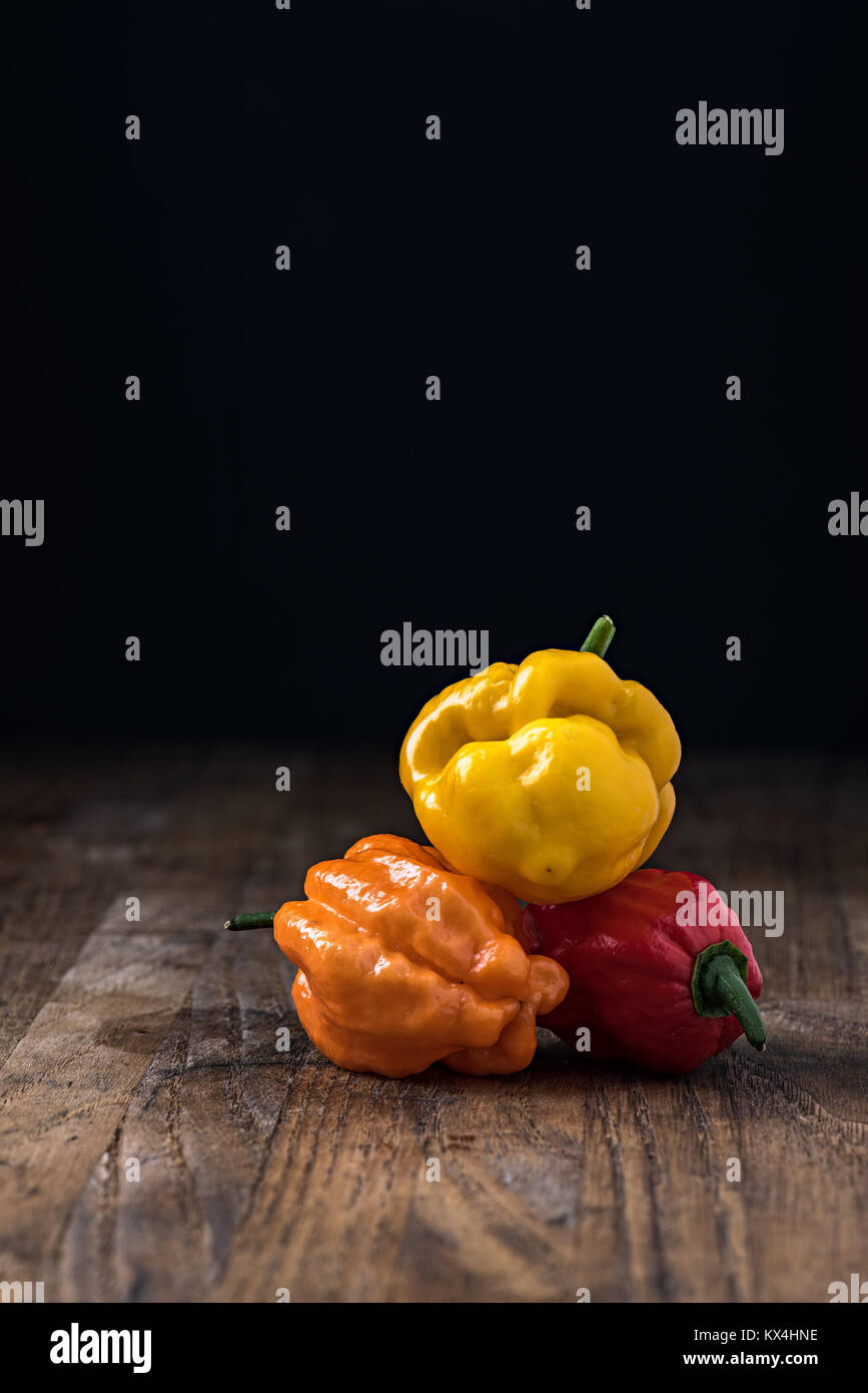 Verschiedene Arten von hot chili peppers am Tisch auf schwarzem Hintergrund und Copyspace Stockfoto