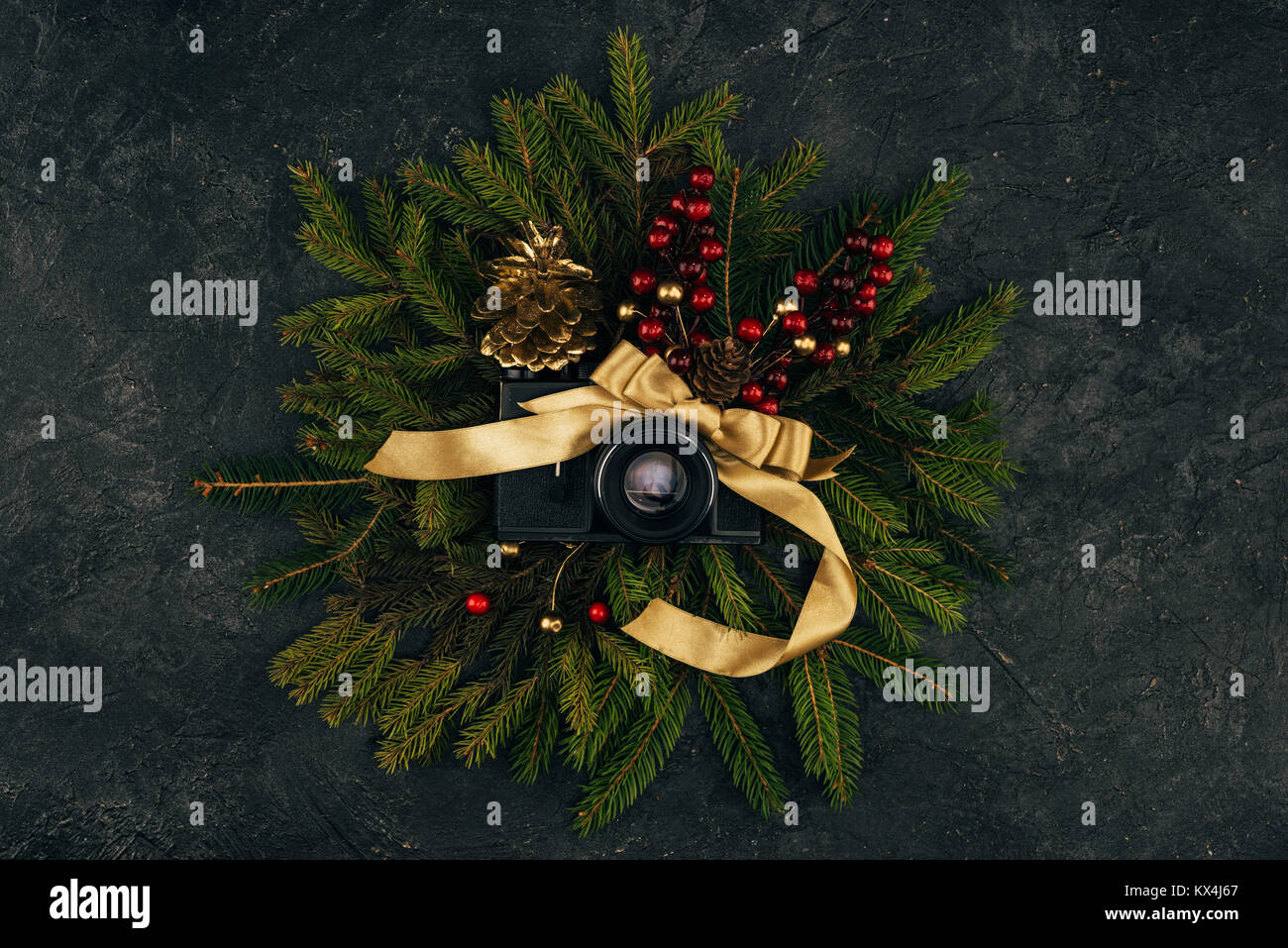 Blick von oben auf die Foto Kamera und festliche Dekorationen auf tannenzweigen auf dunklen Tischplatte Stockfoto