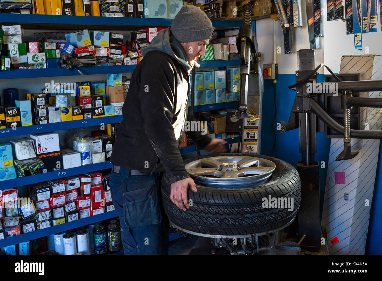 Lehrling Mechaniker für die Reparatur eines platten Reifens mit einem Kompressor in einer Garage. Stockfoto