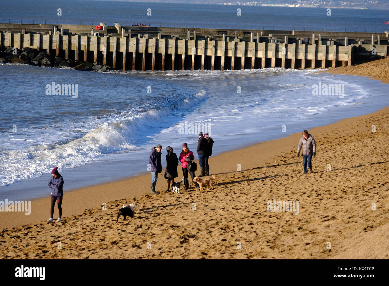 West Bay, Dorset, Großbritannien. 7. Januar 2018. Strand goers Warm gegen die Kälte und Wind einige Winter Sonnenschein an der West Bay zu genießen, an der Küste von Dorset. Credit: Tom Corban/Alamy leben Nachrichten Stockfoto