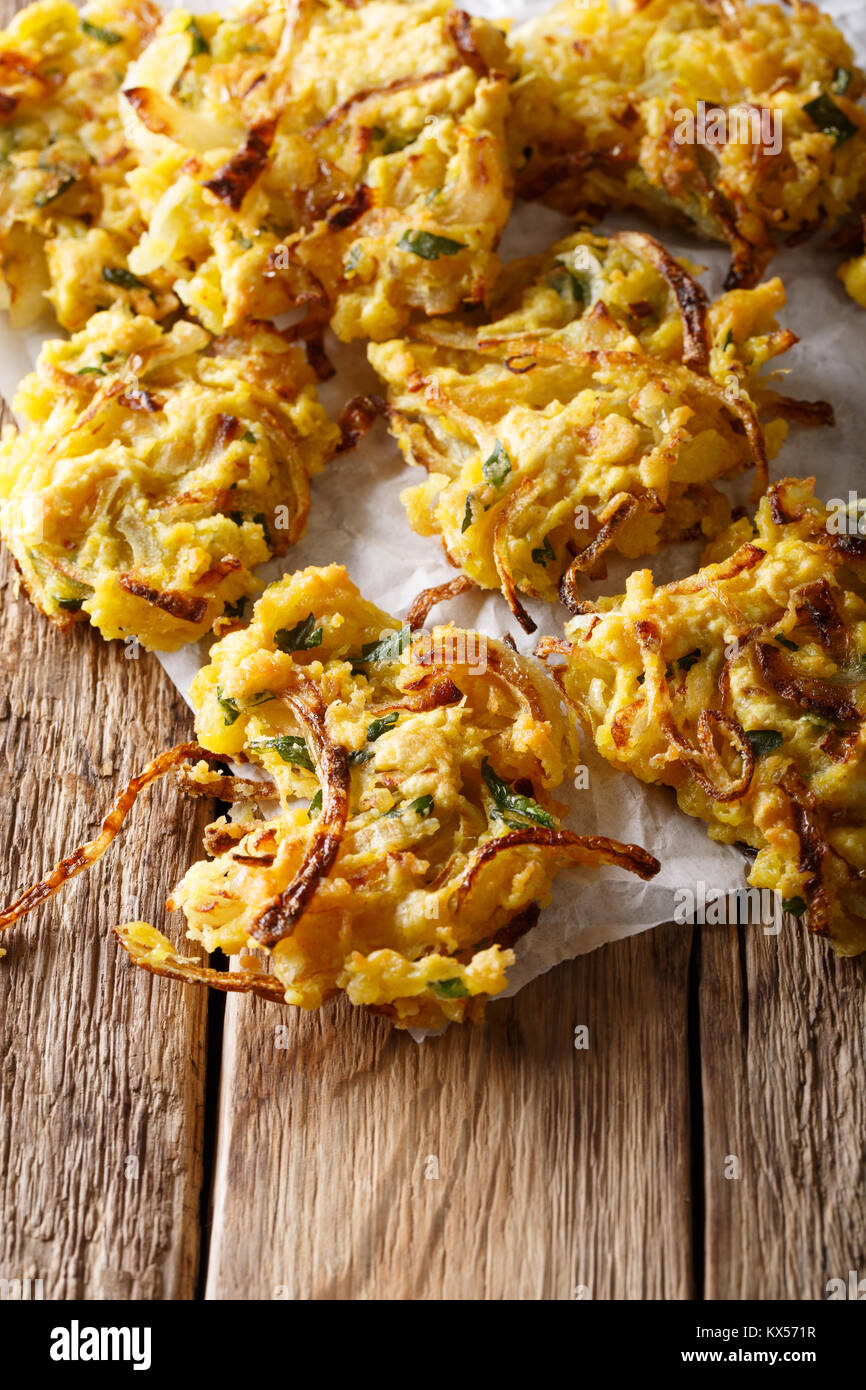 Knusprige Zwiebel Bhajis machen die perfekte Natürlich glutenfrei und veganen Snack oder Starter closeup auf tre Tabelle. Vertikale Stockfoto