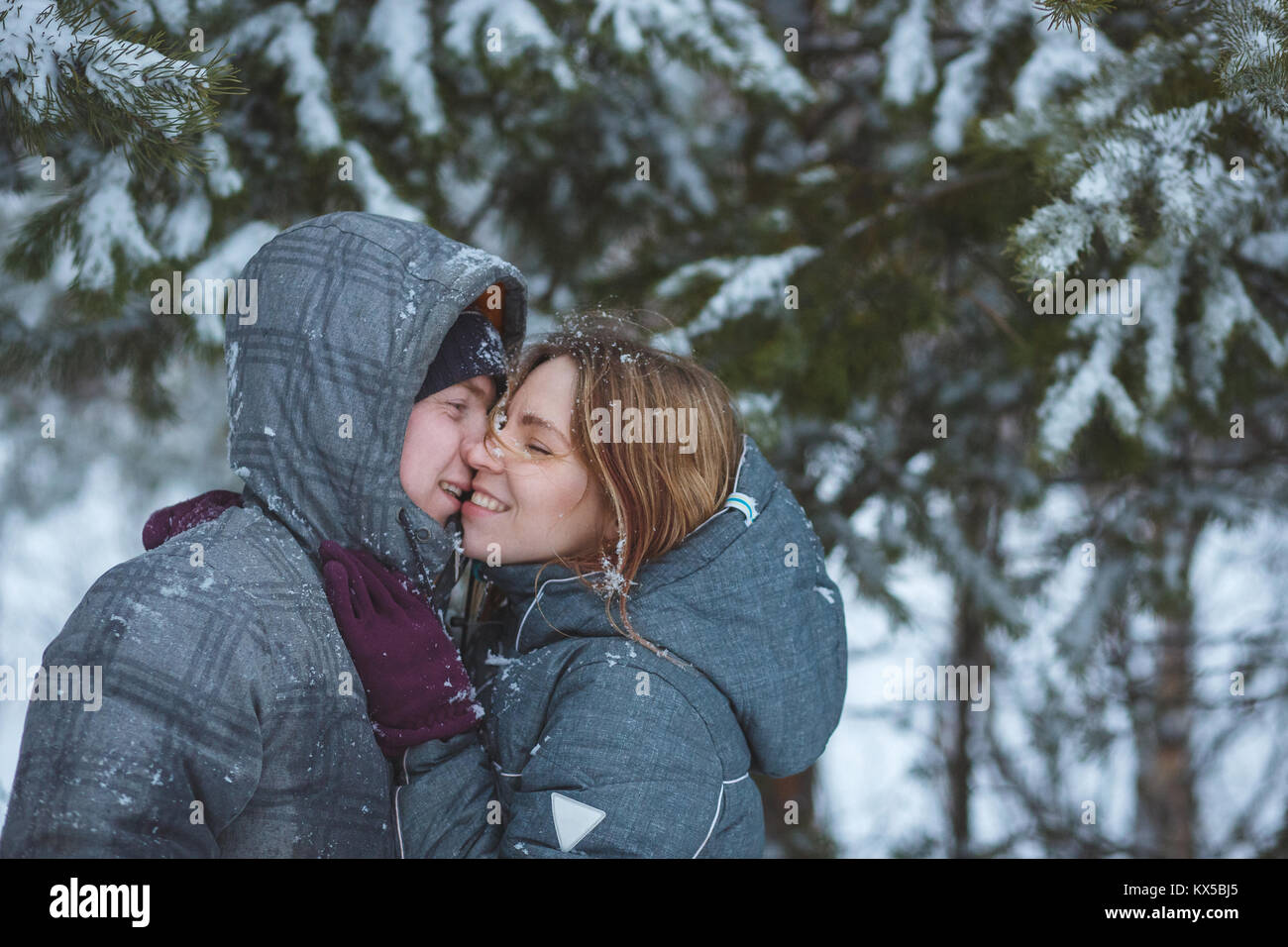 Gerne Schnee paar Küssen unter Tannenzweigen im Winter Wald. Konzept gesunde romantischen Urlaub an der frischen Luft Stockfoto
