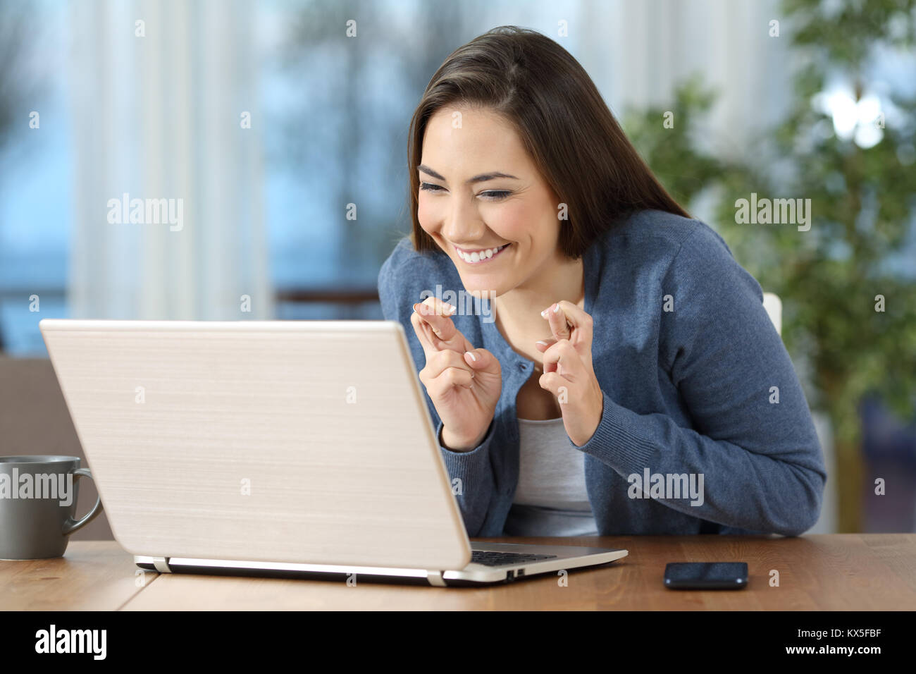 Happy hoffnungsvollen Mädchen die Daumen auf die Überprüfung der Inhalte in einem Laptop zu Hause Stockfoto