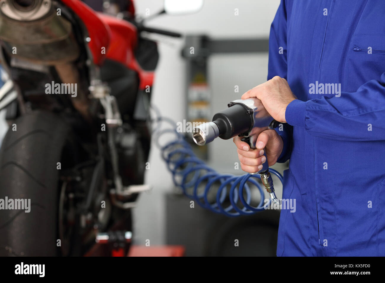 Nahaufnahme von einem Motorrad Mechaniker hand mit einer Druckluftpistole in eine mechanische Werkstatt Stockfoto