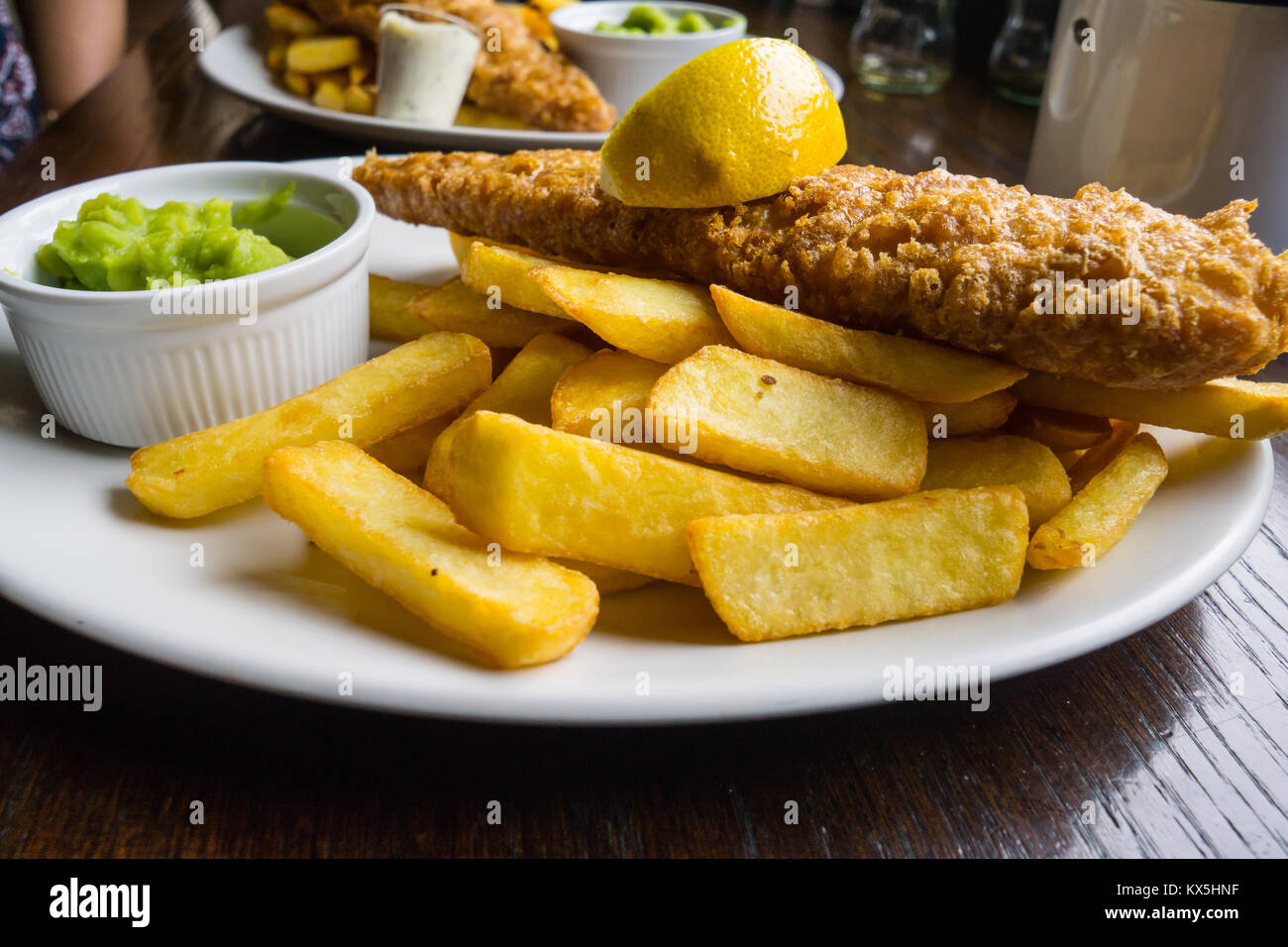 Traditionelle iconic Britische Fisch und Chips mit Erbsenpüree in einem typischen englischen Public House serviert. Stockfoto