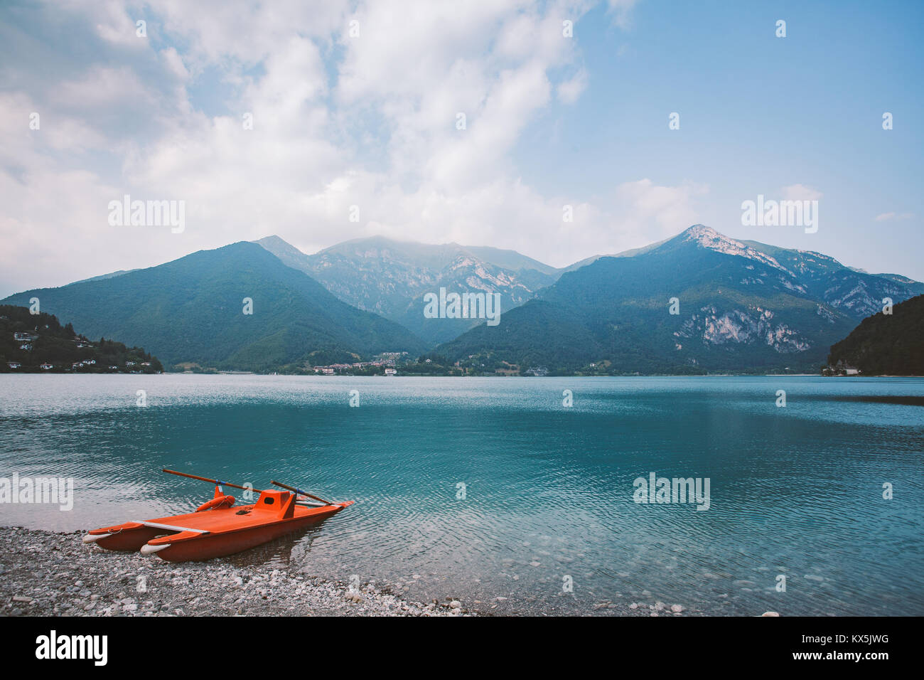 Italien Blick auf einen Bergsee Lago di Ledro mit Strand und ein rettungsboot Katamaran von roter Farbe im Sommer bei bewölktem Himmel. Stockfoto