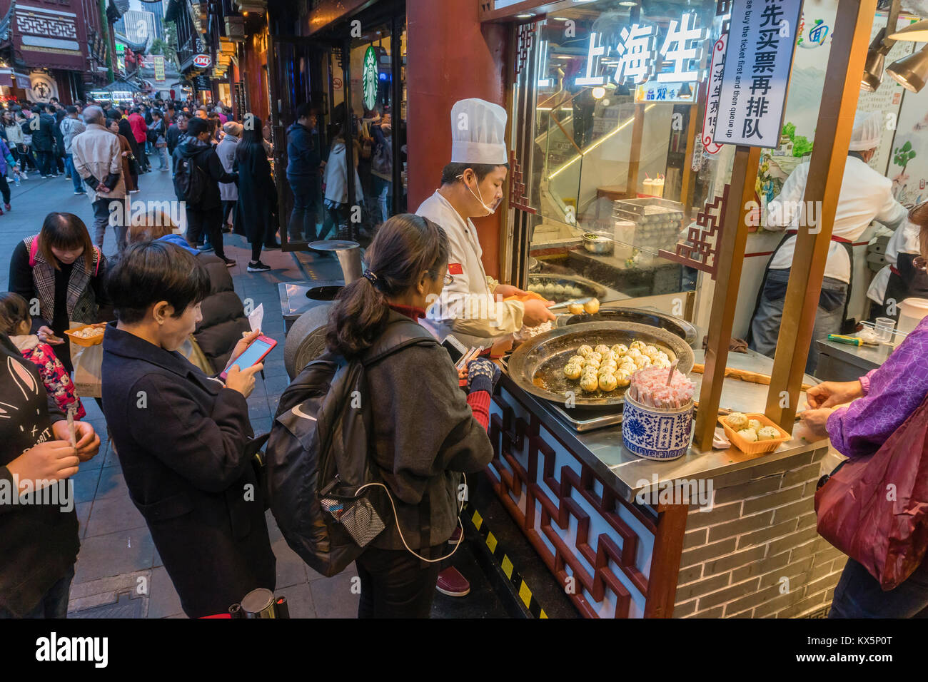 Menschen kaufen in der Pfanne gebratener Shanghai Knödel an einer Garküche Stockfoto