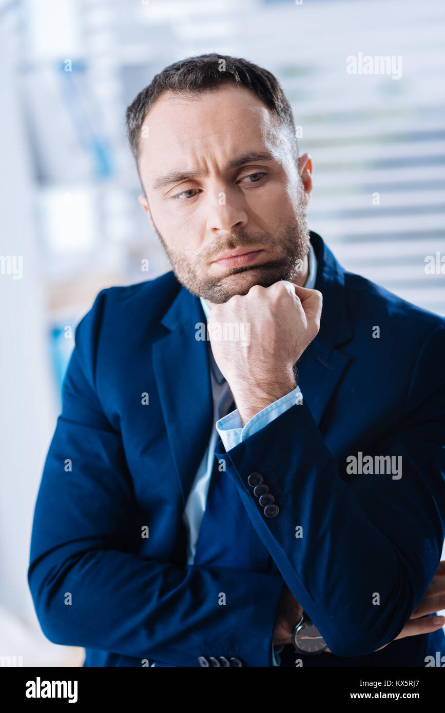 Zuversichtlich smart Geschäftsmann sitzt mit seinem Kinn auf seine Faust Stockfoto