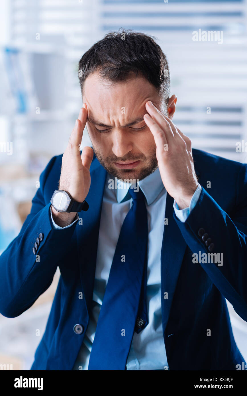 Junger Mann umgekippt und schloss seine Augen, während sein Kopf berühren Stockfoto