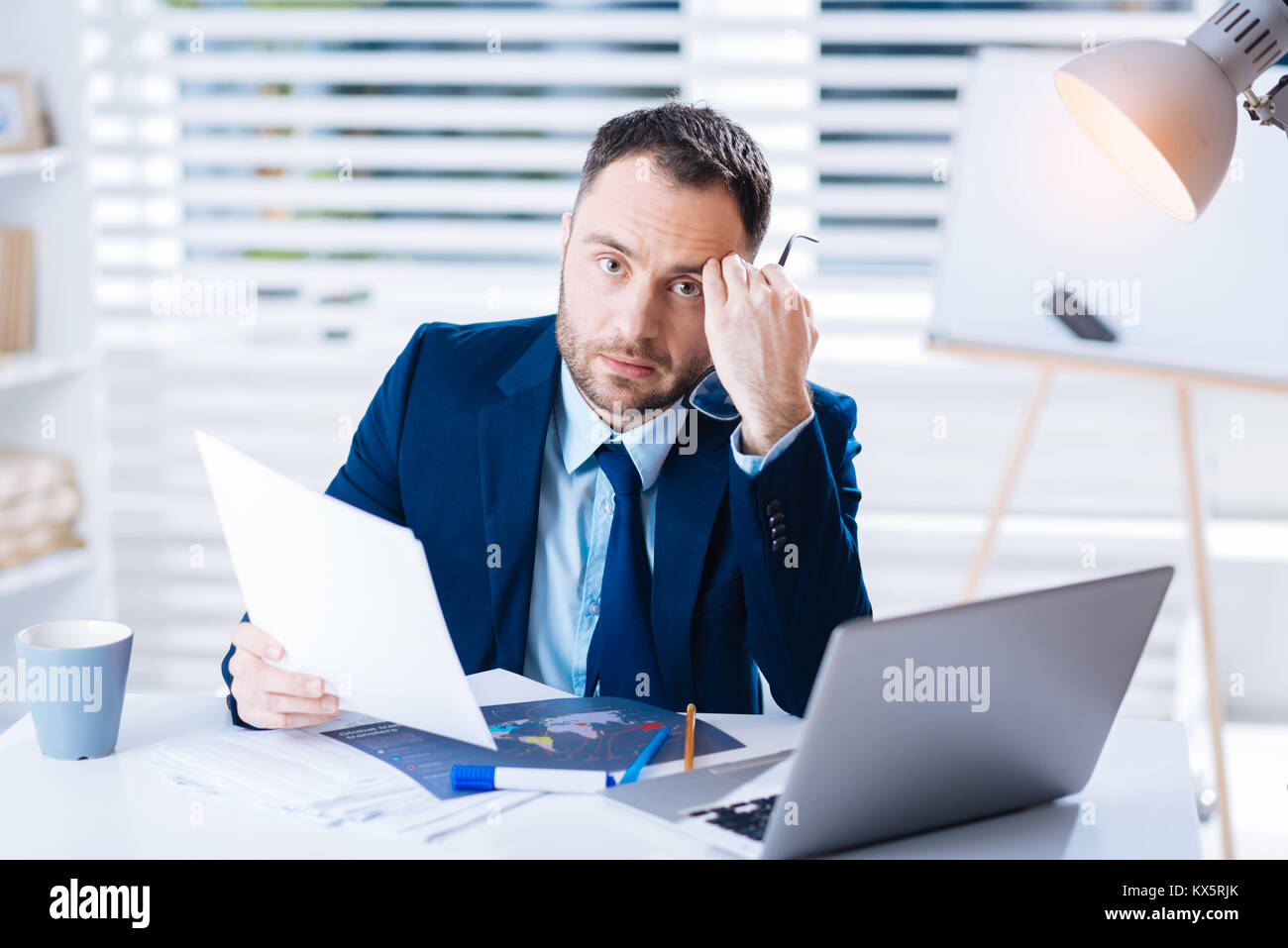 Junge erschöpft Manager sitzt mit seinem Kopf, lehnte sich auf seinen Faust Stockfoto