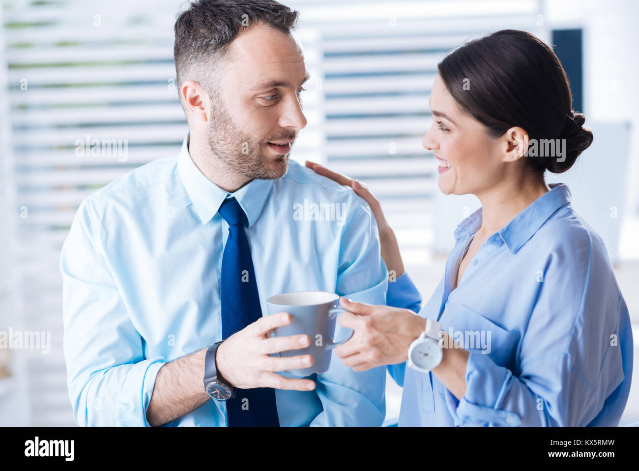 Überrascht Mann lächelnd, während plötzlich eine Tasse Kaffee vom Kollegen Stockfoto