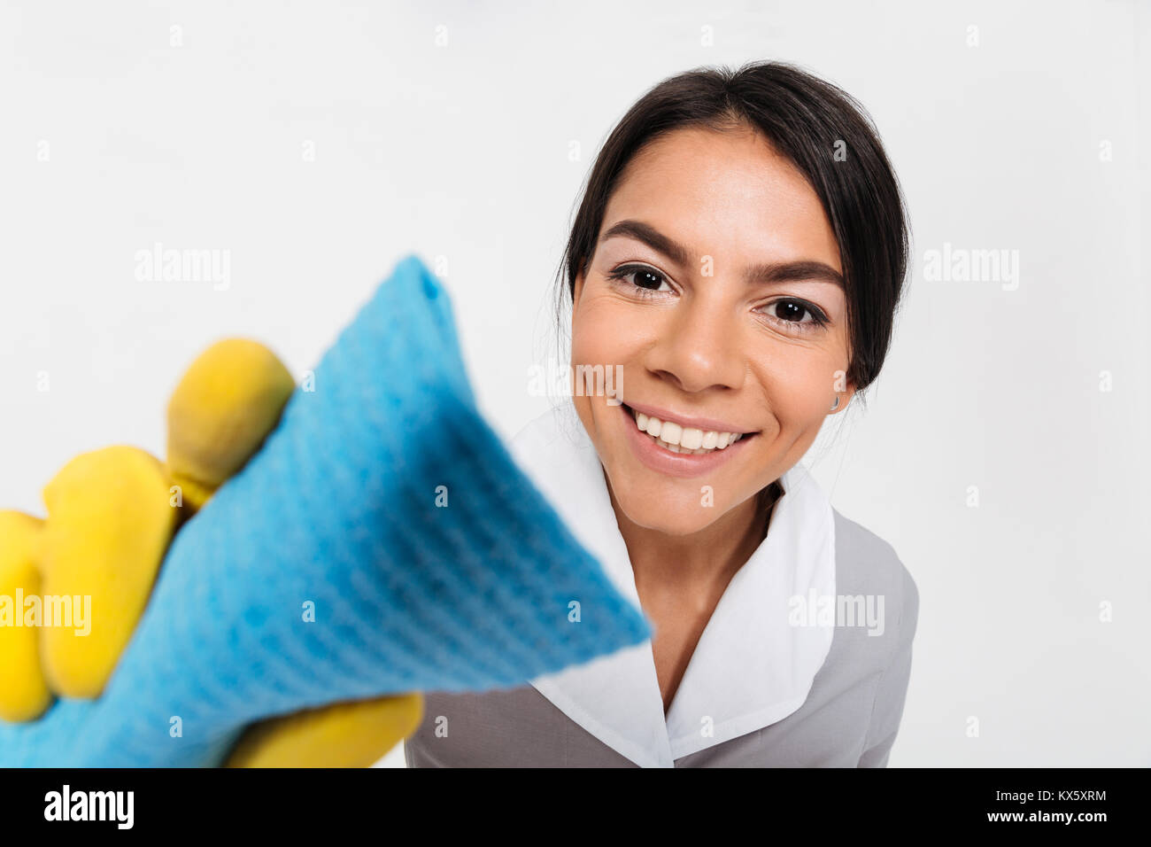 Nahaufnahme von junge lächelnde Haushälterin in gelbe Gummihandschuhe Reinigung Fenster mit der rag auf weißem Hintergrund Stockfoto