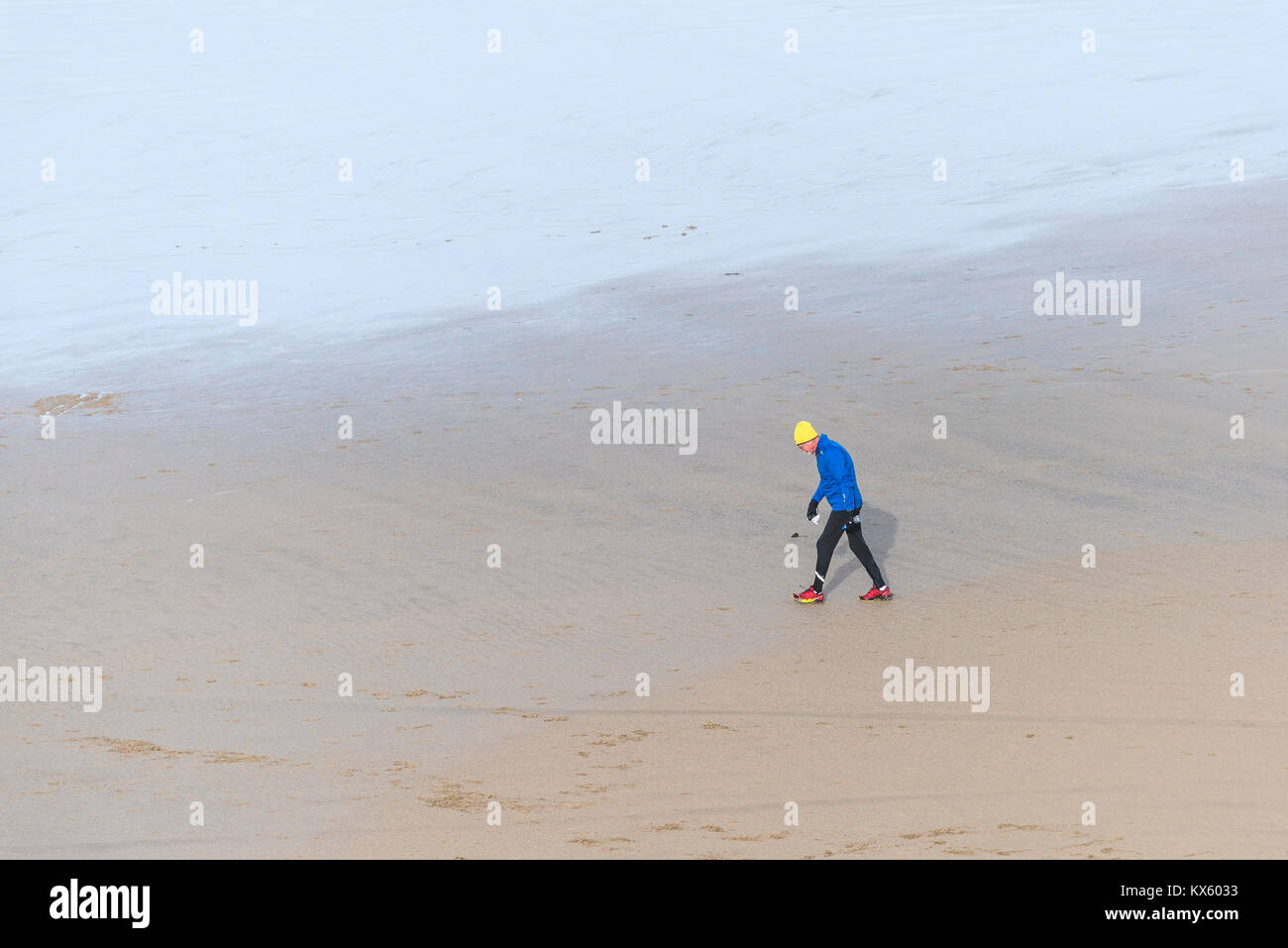 Ein reifer Mann tragen bunte Kleidung wandern Aross ein Strand bei Ebbe. Stockfoto