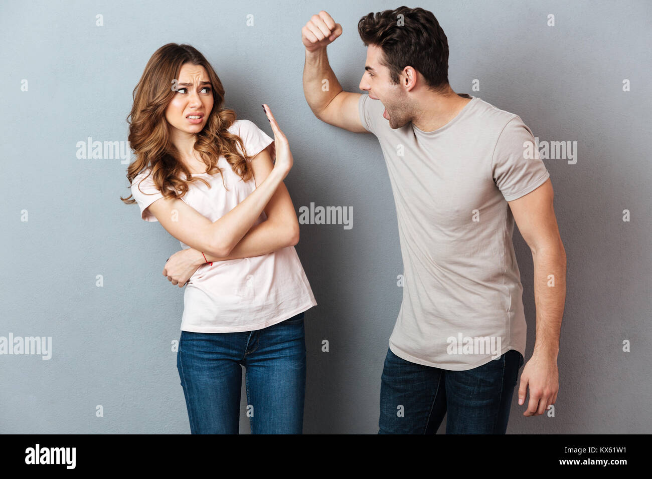 Porträt eines Verrückten wütend Paar in ein Argument und gestikulierend über graue Wand Stockfoto