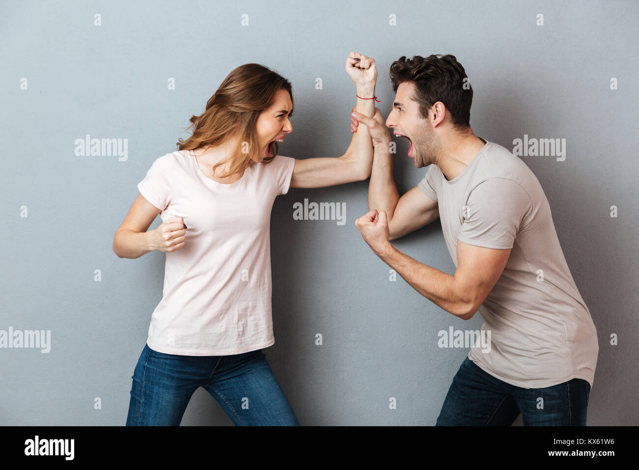 Porträt eines wütenden jungen Paar in ein Argument und kämpft über graue Wand Stockfoto
