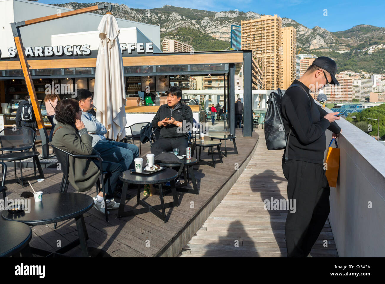 Monaco, Monte Carlo, chinesische Touristen teilen sich Getränke im Starbuck's Cafe Restaurant Terrace Sidewalk in der Nähe des Meeres, Bürgersteig, Straßenszene Stockfoto