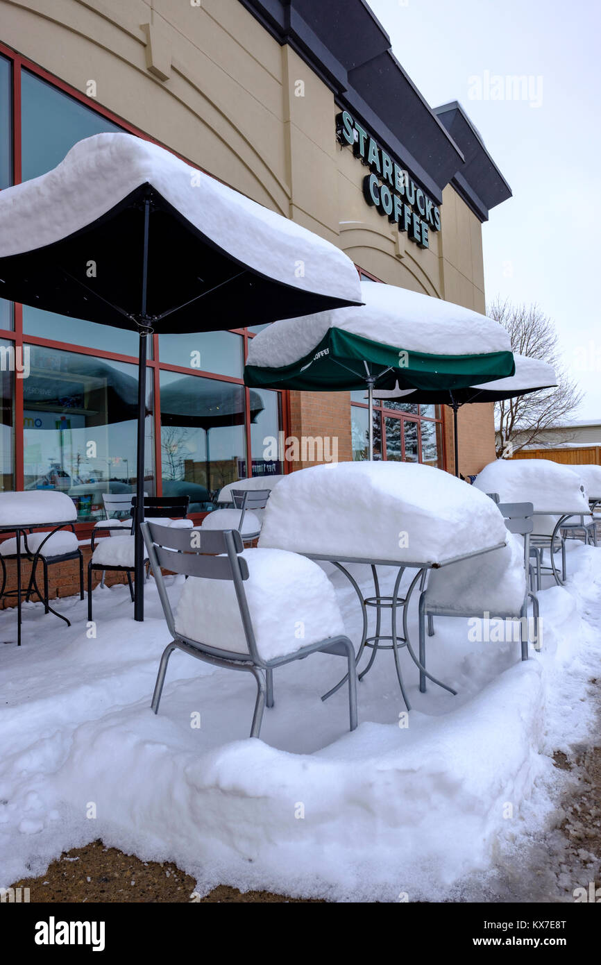 Leere Starbucks Kaffee Bürgersteig Terrasse Tische, Stühle und Sonnenschirme durch frischen Schnee bedeckt, winter Szene, London, Ontario, Kanada Stockfoto