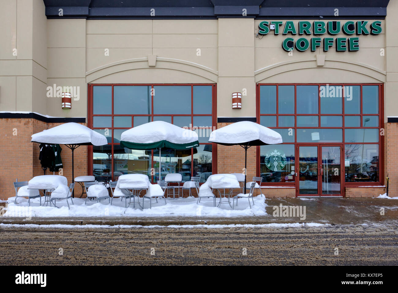 Leere Starbucks Kaffee Bürgersteig Terrasse Tische, Stühle und Sonnenschirme durch frischen Schnee bedeckt, winter Szene, London, Ontario, Kanada Stockfoto