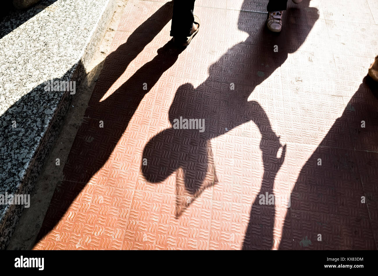 Schatten einer 10-12 Jahre alten Mädchen gehen an der Hand ihrer Mutter in der Straße von Kathmandu Stockfoto