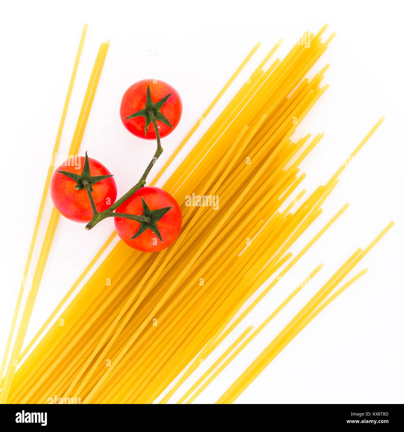 Spaghetti mit Kirschtomaten auf weißem Hintergrund. Ungekochte italienische Getrocknete Spaghetti. Ansicht von oben. Flach. Stockfoto