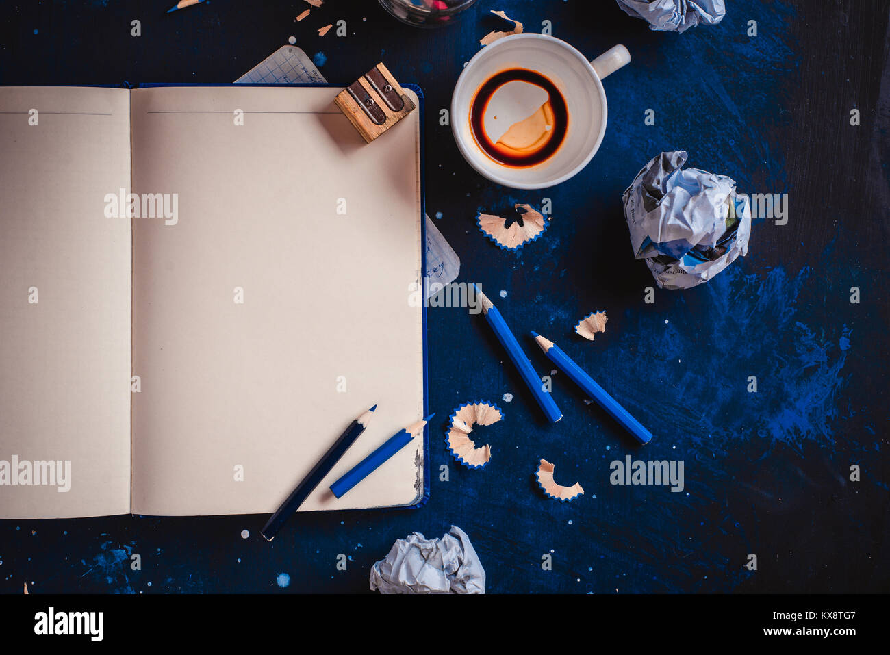 Notepad mit leeren Seiten öffnen, zerknittertes Papier Kugeln, Stifte, Notizblöcke und leere Kaffeetassen auf einem dunklen Hintergrund. Immer noch leben mit dem Schriftsteller Arbeitsplatz. C Stockfoto