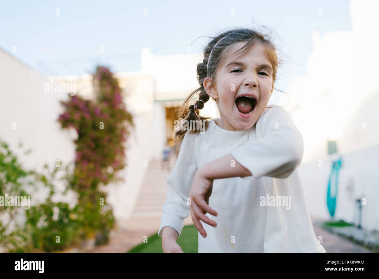 Kleine Kinder spielen und Spaß im Hof ihres Hauses, im Freien über blauen Himmel Stockfoto