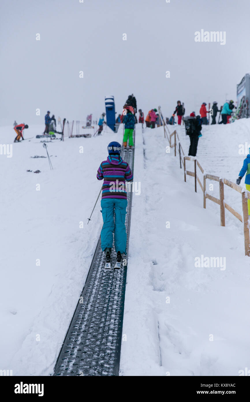 Skifahrer auf einem Band Skilift auf dem Weg in die zweite Etappe der Sessellift bringt Touristen auf den Gipfel des Berges in Szczyrk Skrzyczne, Polen Stockfoto
