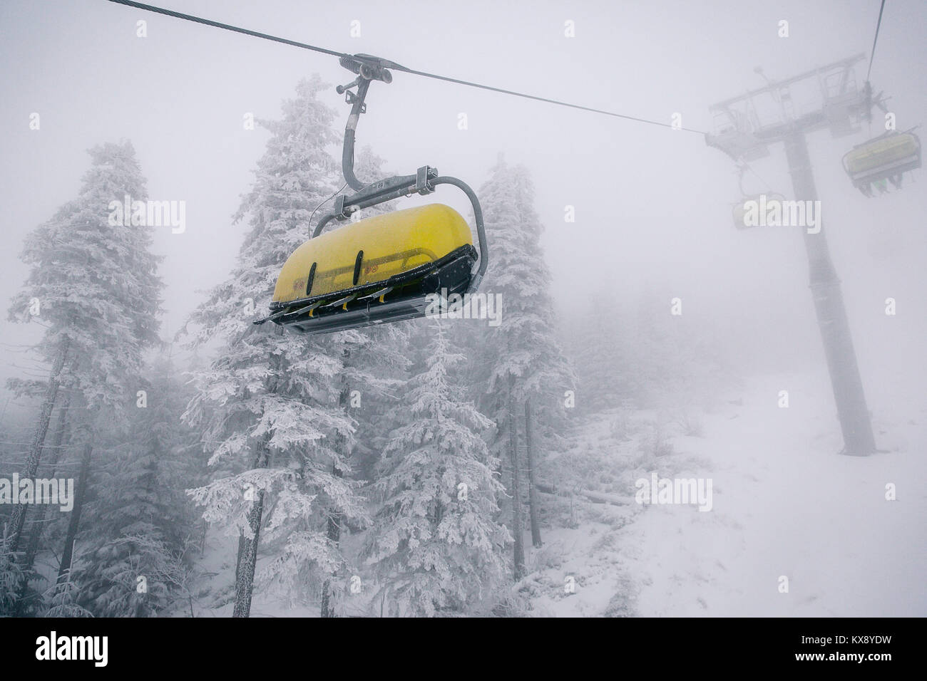 Ski Sessellift bringt Skifahrer und Snowboarder auf den Berg Skrzyczne nach starker Schneefall auf einem nebligen Wintertag in Szczyrk ski resort in Polen Stockfoto