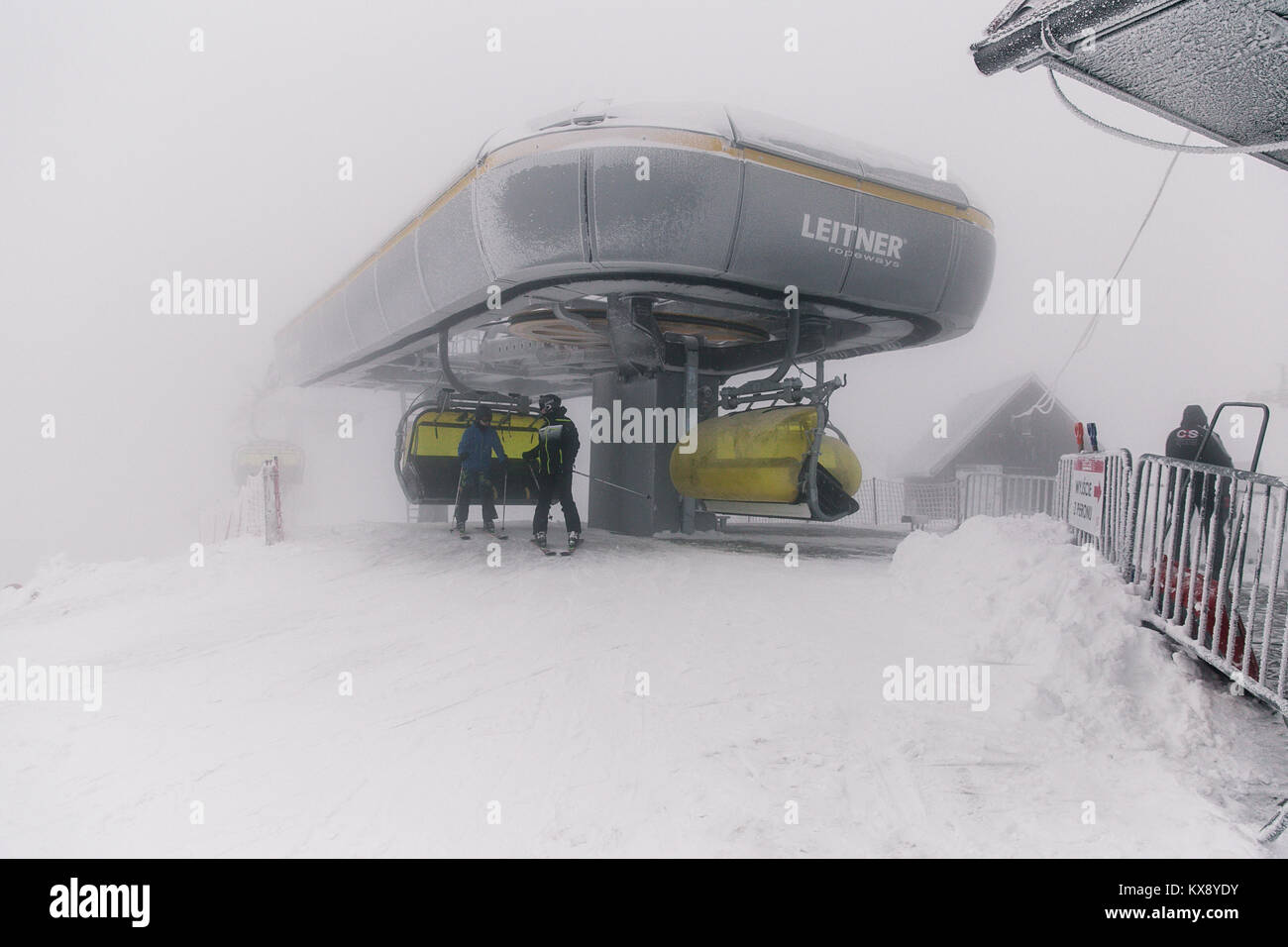Skifahrer, der Sesselbahn auf dem Gipfel Der Berg Skrzyczne in Schnee auf einem nebligen Wintertag in Szczyrk ski resort in Polen Stockfoto